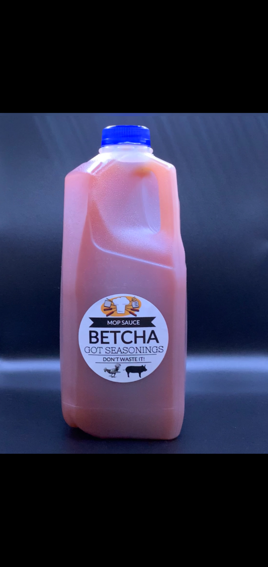 Betcha Got Seasonings Mop Sauce bottle with a blue cap against a dark background